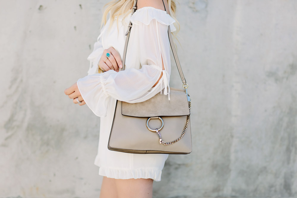 Dash of Darling styles a white off shoulder ruffled hem romper with the Chloe Faye leather bag for the perfect summer look.