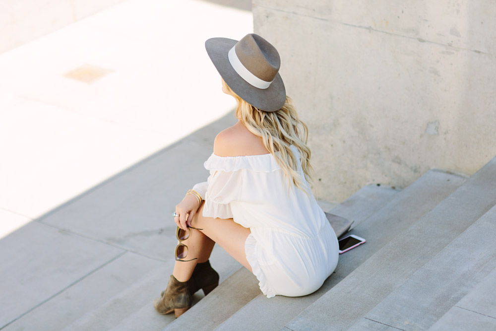 Dash of Darling styles a white off shoulder ruffled hem romper with Celine sunglasses, a wide brim hat and Isabel Marant booties for the perfect summer look.