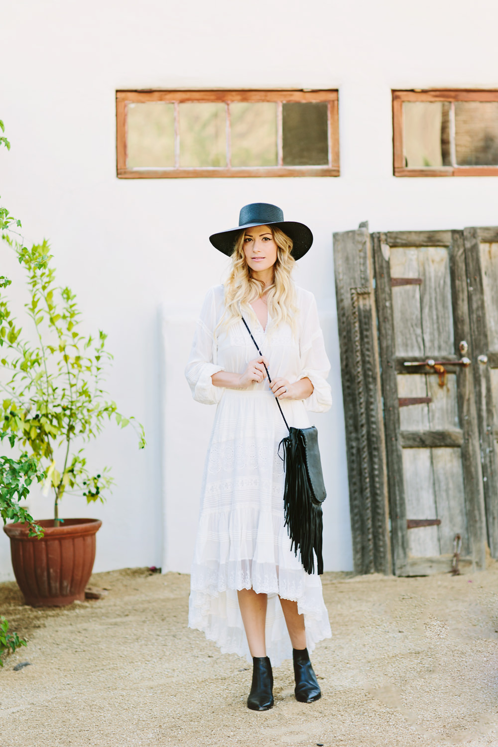 Dash of Darling styles a Spell Designs matching white top and skirt with a Janessa Leone straw boater hat and a Jennifer Haley black fringe bag for a desert bohemian outfit in Palm Springs.