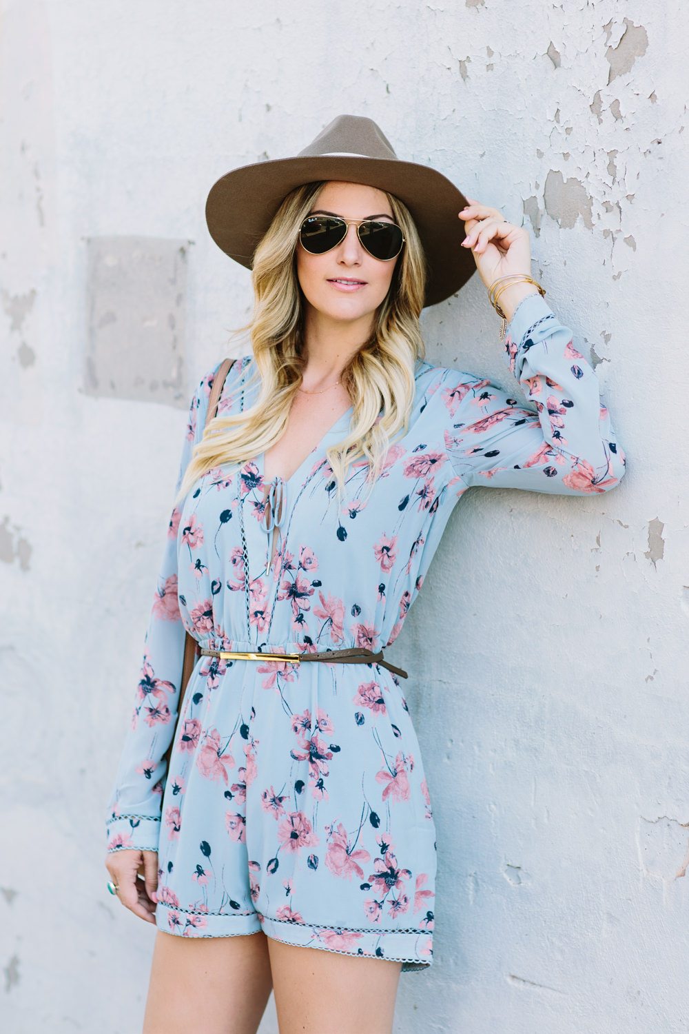 Dash of Darling styles a House of Harlow 1961 blue floral romper from Revolve with a Hat Attack felt fedora, a b-low the belt. rayban sunglasses and a Gucci Soho Disco bag for a bohemian summer outfit.