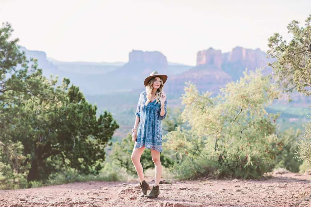 Caitlin Lindquist of the travel blog Dash of Darling styles a summer outfit consisting of a Joie silk shift dress with Isabel Marant Dicker booties and a Hat Attack felt fedora while exploring the desert in Sedona.
