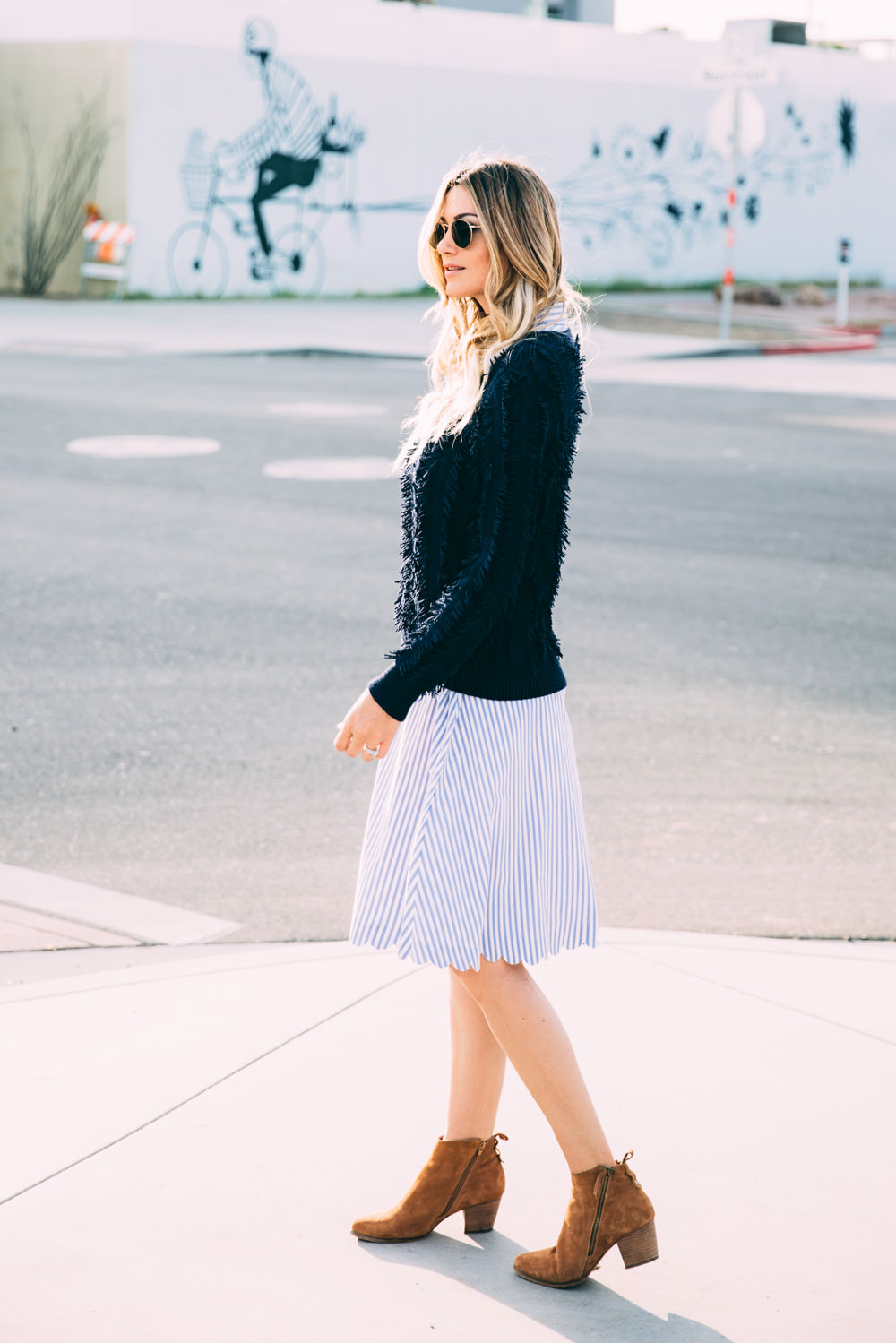 Caitlin Lindquist of Dash of Darling styles a Banana Republic stripe scalloped hem dress with suede boots and a fringe sweater for a fall transition outfit
