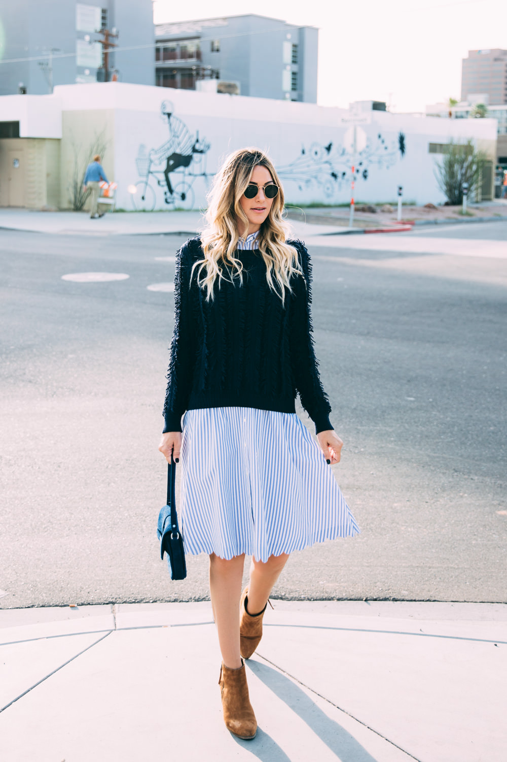 Caitlin Lindquist of Dash of Darling styles a Banana Republic stripe scalloped hem dress with suede boots and a fringe sweater for a fall transition outfit