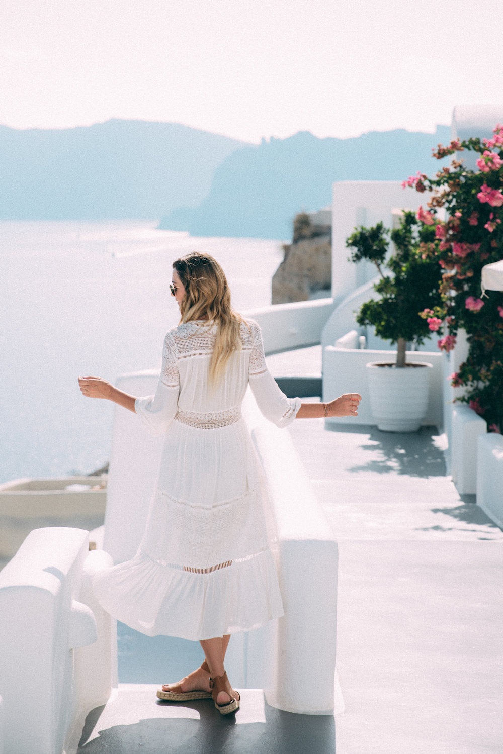 Dash of Darling shares her travels from Oia, Santorini Greece with Royal Caribbean Cruises while wearing a white Spell Designs dress.