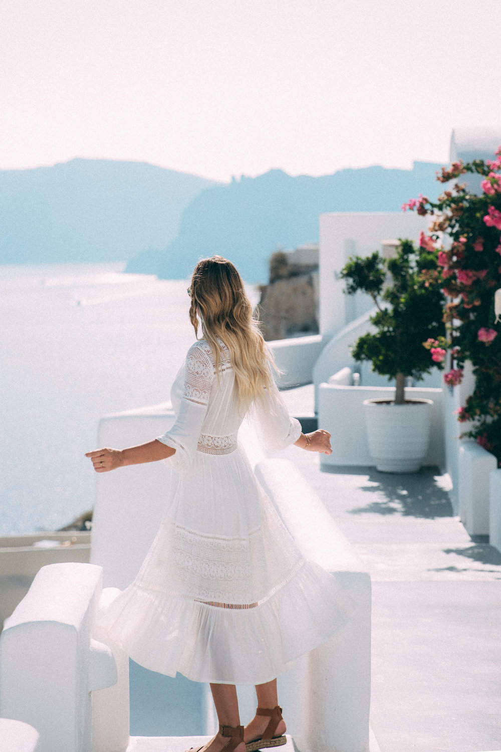 Dash of Darling shares her travels from Oia, Santorini Greece with Royal Caribbean Cruises while wearing a white Spell Designs dress.
