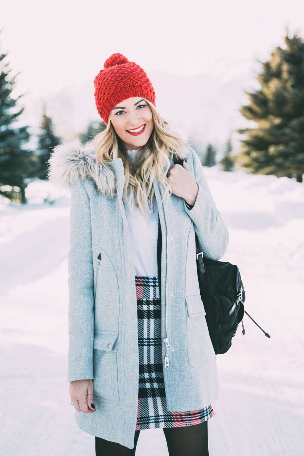 Caitlin Lindquist of the travel blog Dash of Darling shares a holiday winter outfit with Bronzallure in a Topshop plaid skirt, Club Monaco sweater and J.Crew fur hood coat.