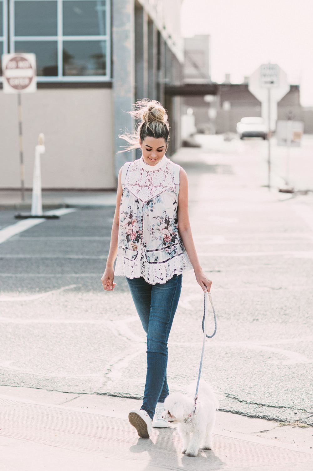 Caitlin Lindquist of the Arizona fashion blog Dash of Darling shares a casual outfit wearing a floral top, white backpack and spring sneakers