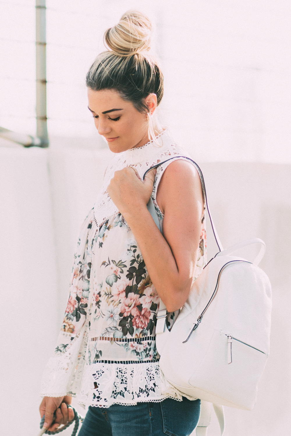 Caitlin Lindquist of the Arizona fashion blog Dash of Darling shares a casual outfit wearing a floral top, white backpack and spring sneakers
